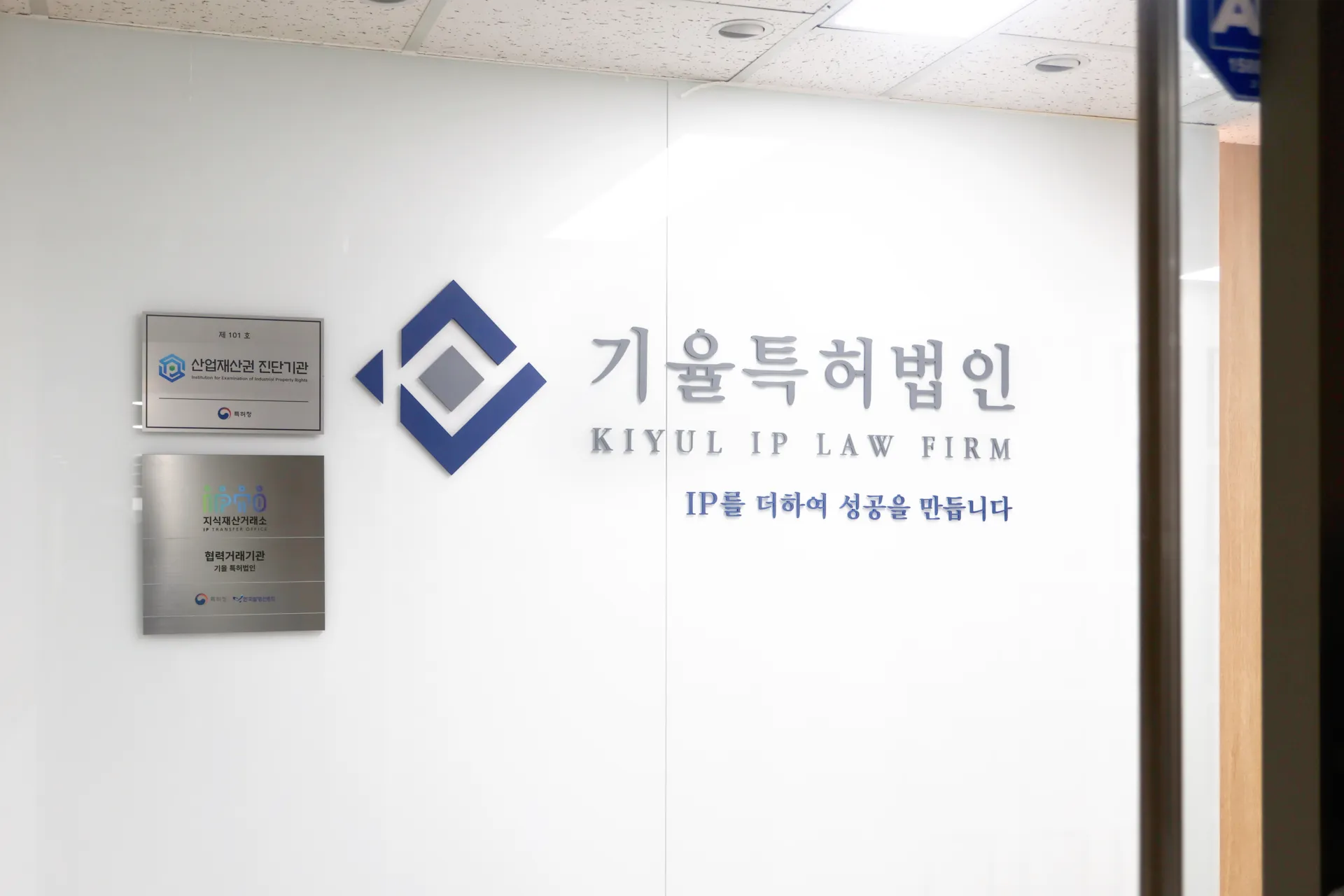 Kiyul IP Law Firm sign on a glass wall with a blue geometric logo and Korean text